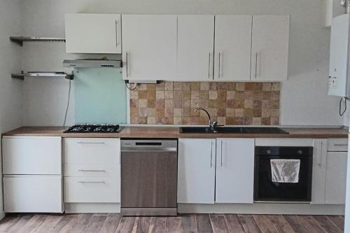 une cuisine avec des armoires blanches et un évier dans l'établissement Maison individuelle 3 chambres, à Le Vaudreuil