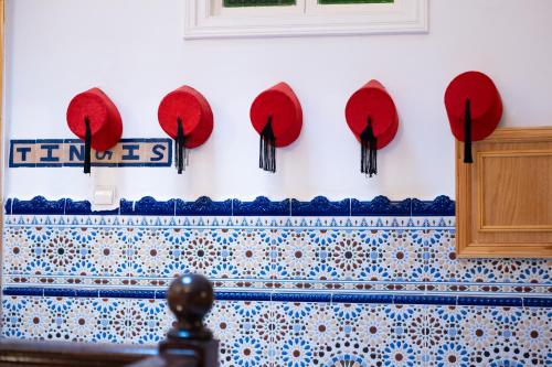 a wall with red hats and blue and white tiles at RIAD AMR in Tangier