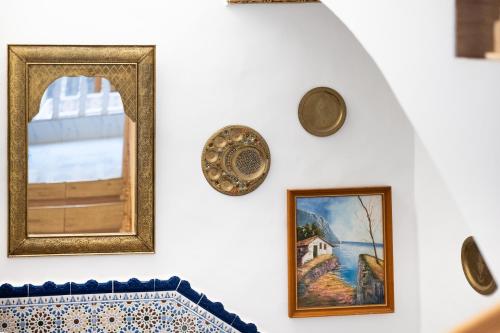 a wall with paintings and plates on it at RIAD AMR in Tangier