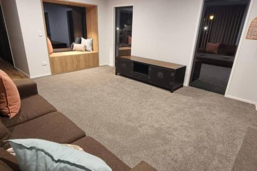a living room with a couch and a tv at Modern Hilltop Retreat with Mountain Views in Rotorua