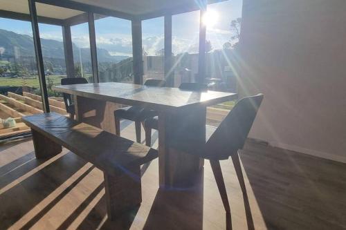 a table and chairs in a room with a view at Modern Hilltop Retreat with Mountain Views in Rotorua