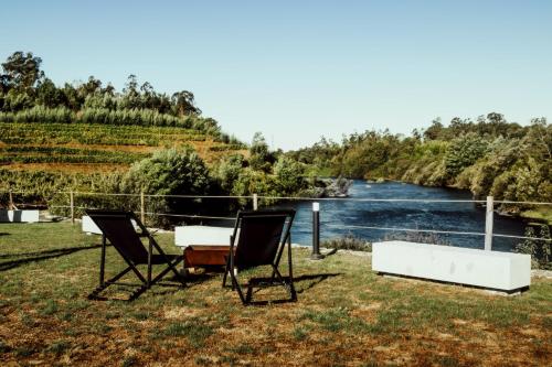 two chairs and a table next to a river at Quinta das Areias - Solar da Pena in Braga