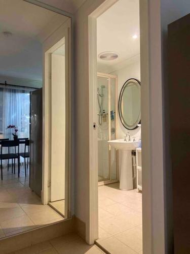 a white bathroom with a sink and a mirror at Cosy, private guest house with pool and private parking in Rockingham