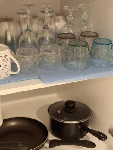 a stove top with a pot and glasses on a shelf at Cosy, private guest house with pool and private parking in Rockingham