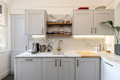 a kitchen with white cabinets and a sink at Stunning Maida Vale Apartment in London
