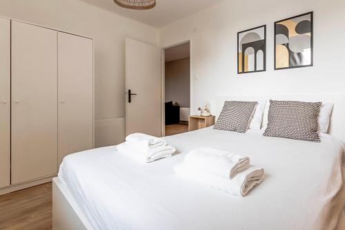 une chambre avec un lit blanc avec des serviettes dessus dans l'établissement Le Manava - Appartement à deux pas du Luxembourg, à Hettange-Grande