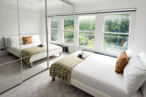 a bedroom with two beds and two windows at Modern and Bright Highgate Gem in London
