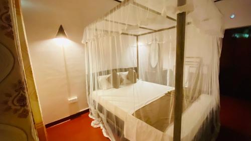 a bedroom with a canopy bed with white curtains at Golden Reef Villa Hikkaduwa in Hikkaduwa