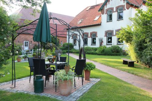 a table with chairs and an umbrella in a garden at Ferienhof Lucht in Mühbrook