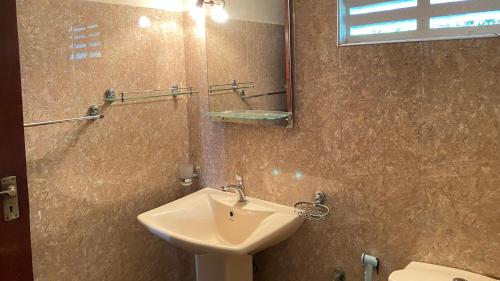 a bathroom with a sink and a mirror and a toilet at Golden Reef Villa Hikkaduwa in Hikkaduwa