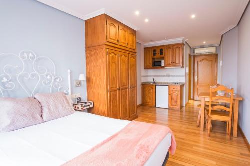 a bedroom with a white bed and a kitchen at InsideHome Porta do Sol in Vigo