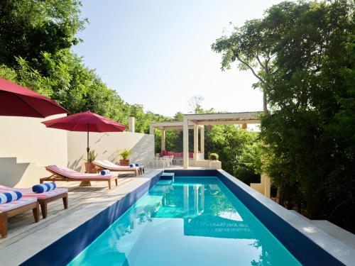 a swimming pool with chairs and umbrellas next to a house at Cocolia Hotel in Mazunte