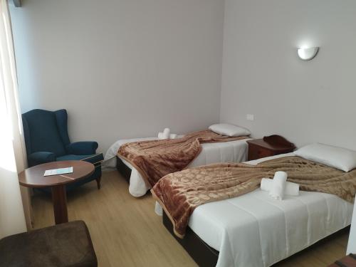 a hotel room with three beds and a chair at Alojamento Central II in Funchal