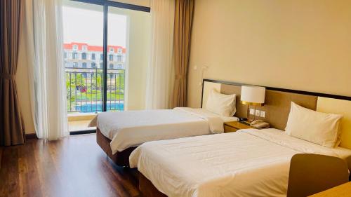a hotel room with two beds and a window at Vinholidays Fiesta Phu Quoc in Phu Quoc