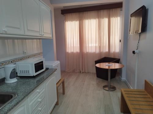 a kitchen with a microwave and a small table at Alojamento Central II in Funchal