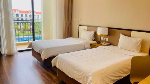 a hotel room with two beds and a window at Vinholidays Fiesta Phu Quoc in Phu Quoc