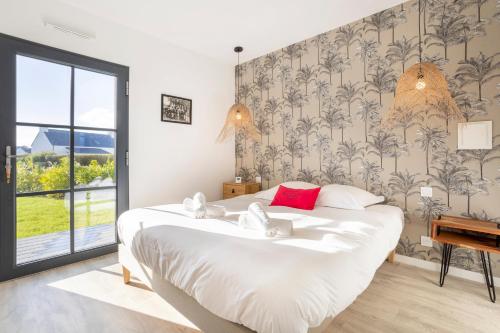 a bedroom with a large white bed with red pillows at Ô Vagues de la Torche à 300m plage in Penmarcʼh