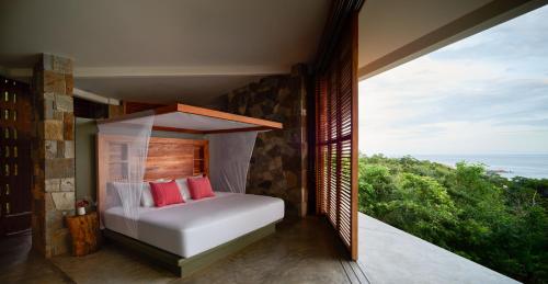 a bedroom with a bed with a view of the ocean at Cocolia Hotel in Mazunte