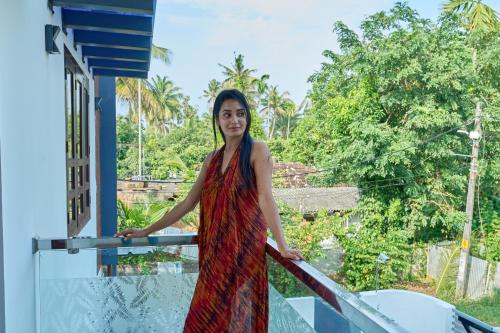 a woman in a red dress standing on a balcony at Venice Rosedale in Alleppey