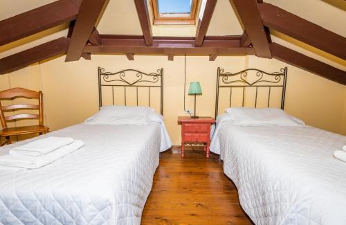 two twin beds in a room with wooden floors at Casa Horno in Robledo