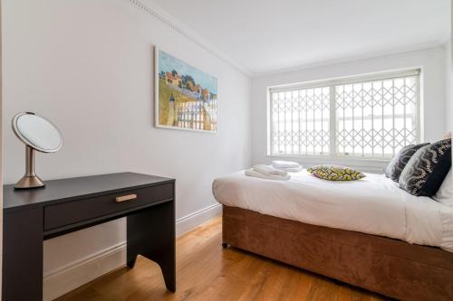 a bedroom with a bed with a desk and a window at Gorgeous Kentish Town Flat in London