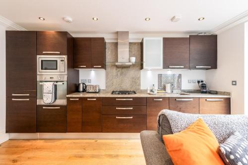 a kitchen with wooden cabinets and a couch in a room at Gorgeous Kentish Town Flat in London