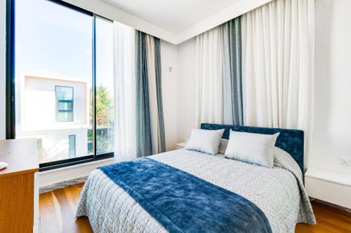 a bedroom with a blue bed and large windows at Villa Laurus 4 by Ezoria Villas in Paphos