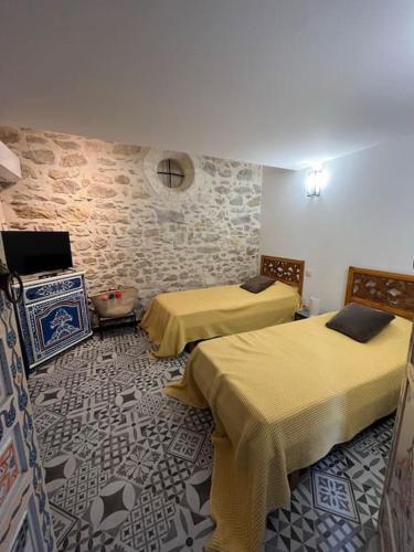Cette chambre comprend 2 lits et un mur en pierre. dans l'établissement Traditional Riad Camargue Arles, à Arles