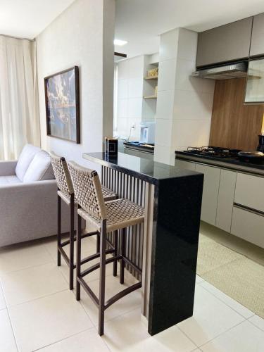 a kitchen with two chairs and a black counter top at Refúgio Maravista #1908 - piscina, hidro, wi-fi, para até 6 pessoas in Maceió