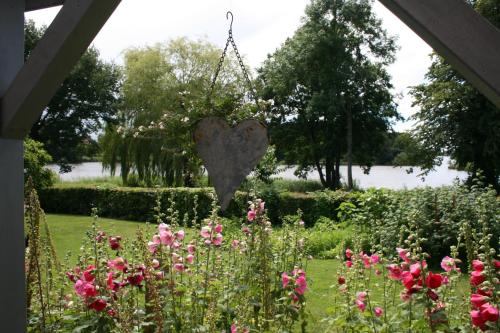 a heart hanging from a chain in a garden with flowers at Ferienhof Lucht in Mühbrook