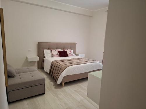 a white bedroom with a bed and a chair at Mariam Royal Apartment & Rooms in Reggio Calabria