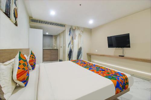 a bedroom with a white bed and a flat screen tv at FabHotel SSR Fern Suites - 100M from GSM Mall Madeenaguda in Lingampalli