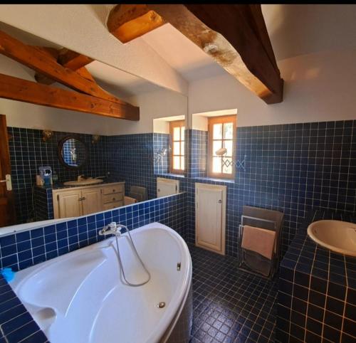La salle de bains est pourvue de carrelage bleu, d'une baignoire et d'un lavabo. dans l'établissement Maison de Caractère située au coeur des domaines viticoles de BANDOL, à La Cadière-dʼAzur