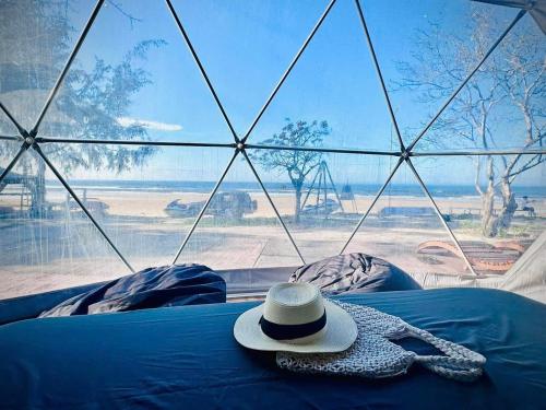 a hat sitting on top of a bed with a window at Lu Adventure-Camp in Ke Ga