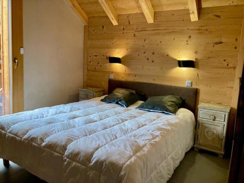 une chambre avec un grand lit avec un mur en bois dans l'établissement Appartement lumineux 3 pièces, 6 pers, à 250m des pistes, animaux admis - FR-1-811-11, à Les Deux Alpes