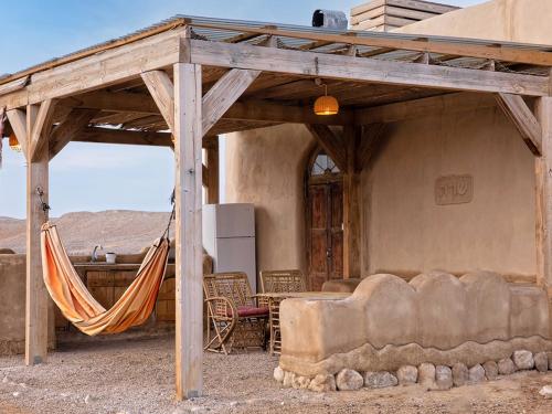 a hammock in front of a house in the desert at Desert Days mud cabin's Resort in Zuqim
