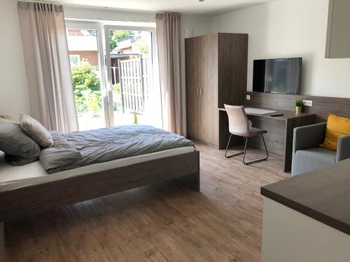 a bedroom with a bed and a desk and a tv at Living-Apartments-Harsewinkel in Harsewinkel