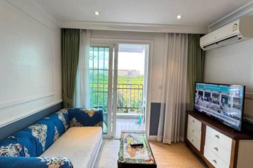 a living room with a blue couch and a tv at Seven Seas Cote D'azur Jomtien in Na Jomtien