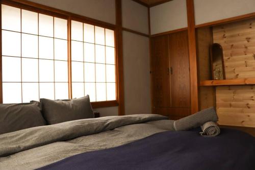 a bed in a room with two large windows at Tob-inn Myoko in Myoko