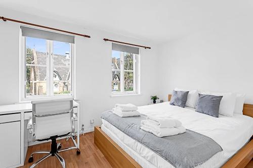 ein weißes Schlafzimmer mit einem Schreibtisch und einem Bett in der Unterkunft Beautiful Three-Bedroom House in Richmond in Richmond upon Thames
