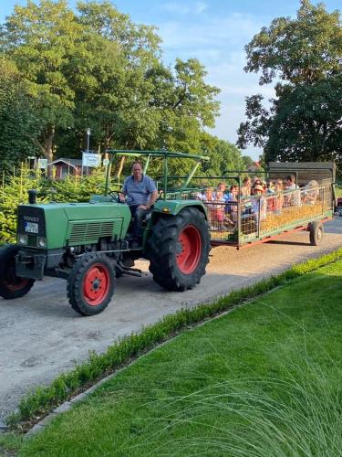 a man driving a tractor pulling a cart with people at Ferienhof Lucht in Mühbrook