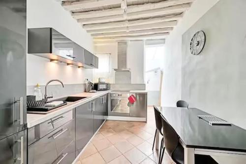 une cuisine avec une table et une horloge au mur dans l'établissement Loge de l'Opéra à 200 m du Palais des Papes, à Avignon