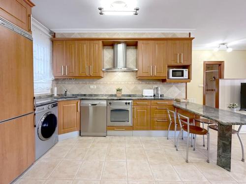 a kitchen with wooden cabinets and a marble counter top at Apartamento en centro de Laredo in Laredo