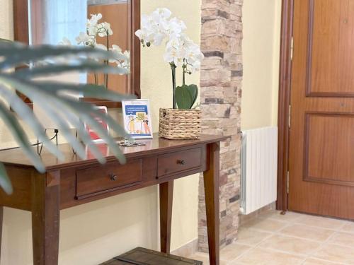 a wooden table with a vase of flowers on it at Apartamento en centro de Laredo in Laredo