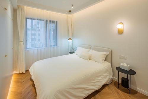 a white bed in a room with a window at Tonight Homestay South Shanxi Road Shanghai in Shanghai