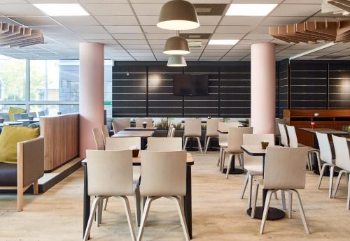 a dining room with tables and chairs and a flat screen tv at B&B HOTEL Paris Nord 2 CDG Aéroport in Roissy-en-France