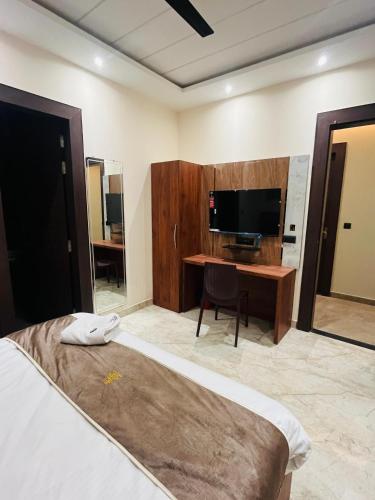 a bedroom with a bed and a desk with a television at Goel Villa and Hotel in Allāhābād Junction