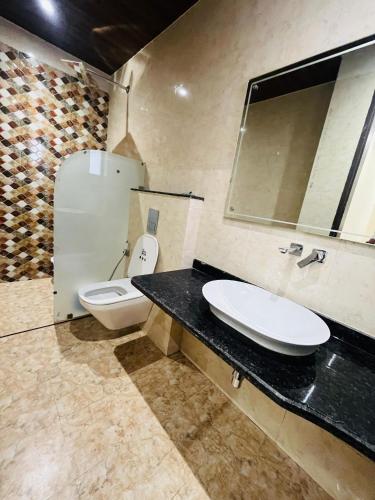 a bathroom with a toilet and a sink and a mirror at Goel Villa and Hotel in Allāhābād Junction