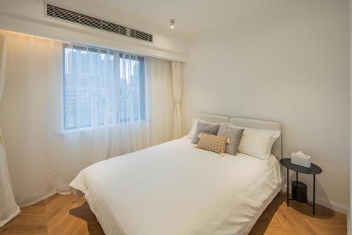 a white bed in a room with a window at Tonight Homestay South Shanxi Road Shanghai in Shanghai