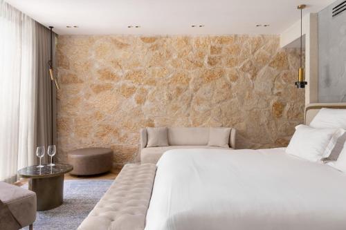 a bedroom with a white bed and a stone wall at Gordonia Ma'ale Hahamisha in Maale Hachamisha